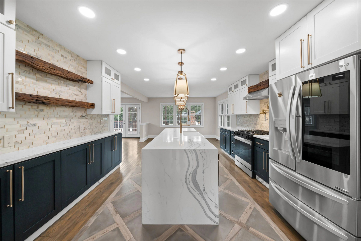A finished galley kitchen with navy lower cabinets and a marble-look waterfall island